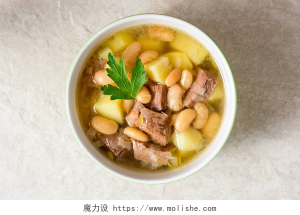 俯拍一碗牛肉汤土豆、 豆类和韭葱石背景上的陶瓷碗里的牛肉汤.